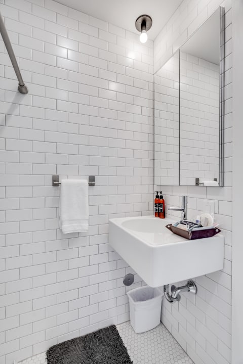 Modern bathroom with white subway tiles, wall-mounted sink, and toiletries.