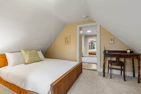 Cozy attic bedroom with sloped ceiling and wooden furniture.