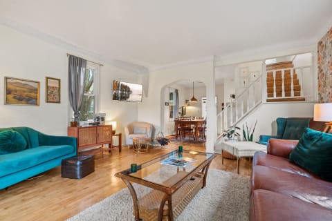 Cozy living room with teal and brown sofas, a glass coffee table, and a dining area in the background.