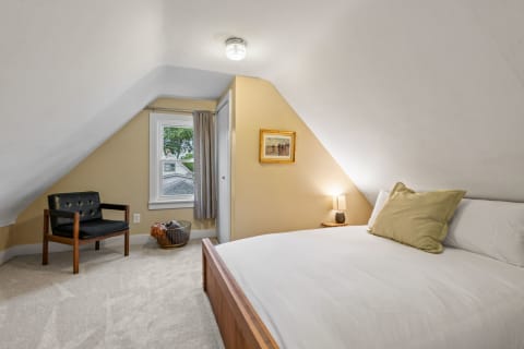 Cozy attic bedroom with sloped ceiling, a bed, and a leather chair.