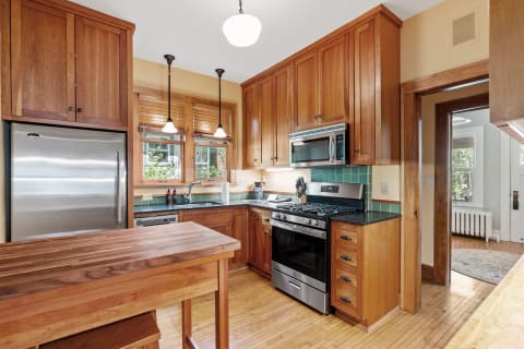 Warm kitchen with wooden cabinets and stainless steel appliances.