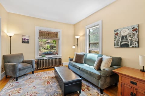 Living room featuring a gray sofa, black ottoman, and large windows with a view.