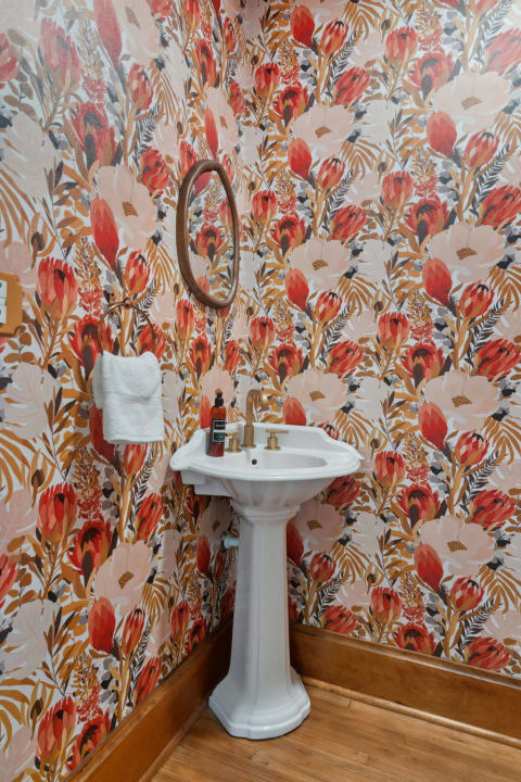 Bright bathroom with floral wallpaper and a white pedestal sink.