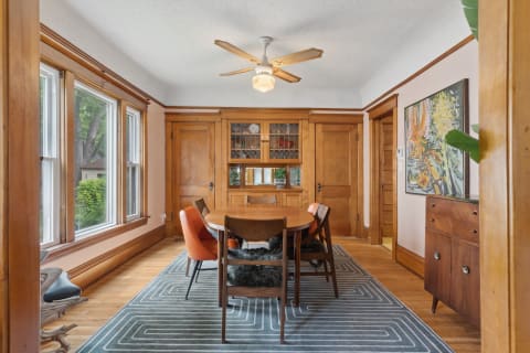 A warm dining room with wooden furniture, large windows, and modern decor accents.