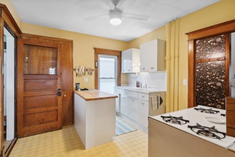 Cozy kitchen with vintage charm, featuring yellow walls, a butcher block island, and white cabinetry.