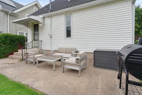 An outdoor seating area featuring a modern sofa and grill next to a house.