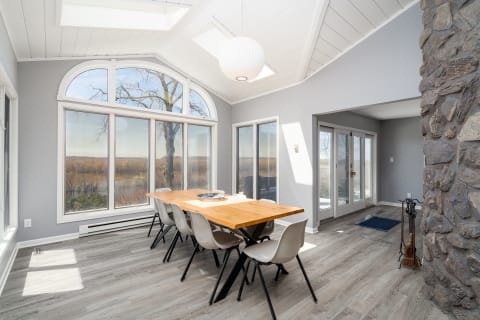 Modern dining room with a wooden table and large windows overlooking nature.