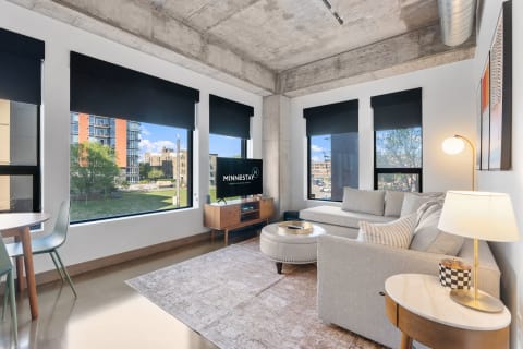 Modern living room featuring a gray sofa, large windows, and a flat-screen TV.