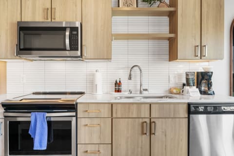 Modern kitchen featuring light wood cabinets, stainless steel appliances, and a white countertop.