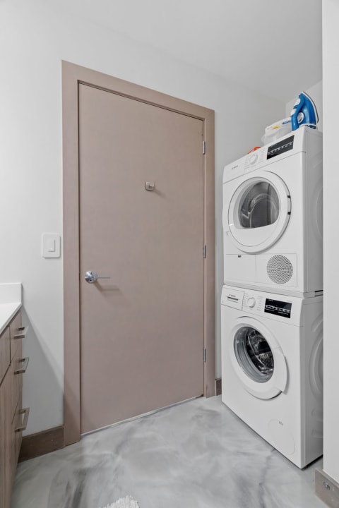 Compact laundry room with stacked washer and dryer and light cabinetry.
