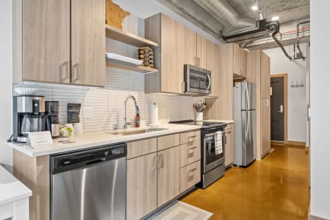 A contemporary kitchen featuring wooden cabinets, stainless steel appliances, and a decorative map.