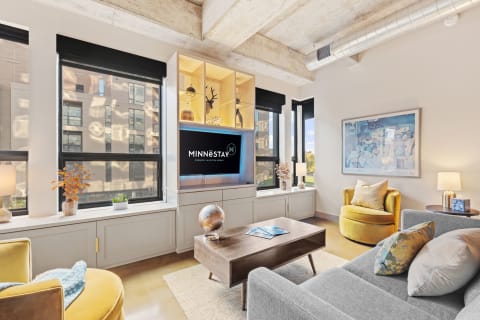 Modern living room with gray sofa, yellow accent chair, and large windows.