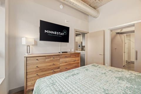 Stylish bedroom with a wall-mounted TV and wooden dresser.