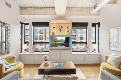 Stylish living room with a concrete ceiling, modern furniture, and large windows offering city views.