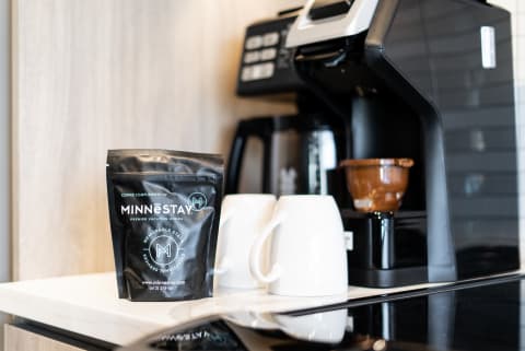 Coffee pouch from Minnestay with white mugs and a coffee machine in a contemporary kitchen.