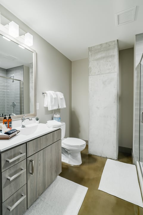 Contemporary bathroom featuring a double sink vanity, concrete column, and stylish shower area.
