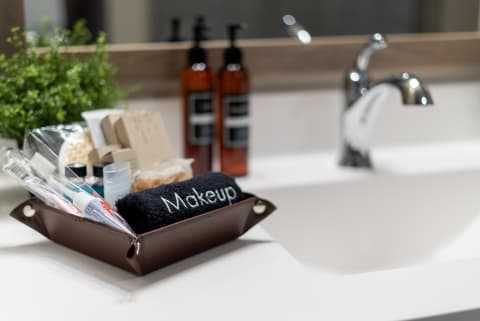 Brown tray with makeup items and a black towel in a contemporary bathroom setting.