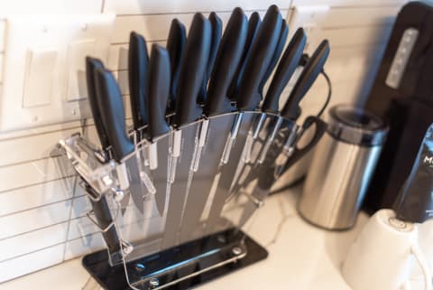 A knife block with black-handled knives on a countertop beside kitchen appliances.