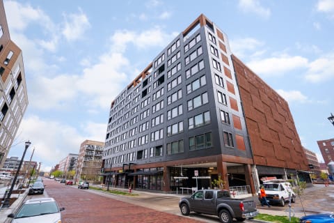 Modern building with large windows and rust-colored accents on a city street.