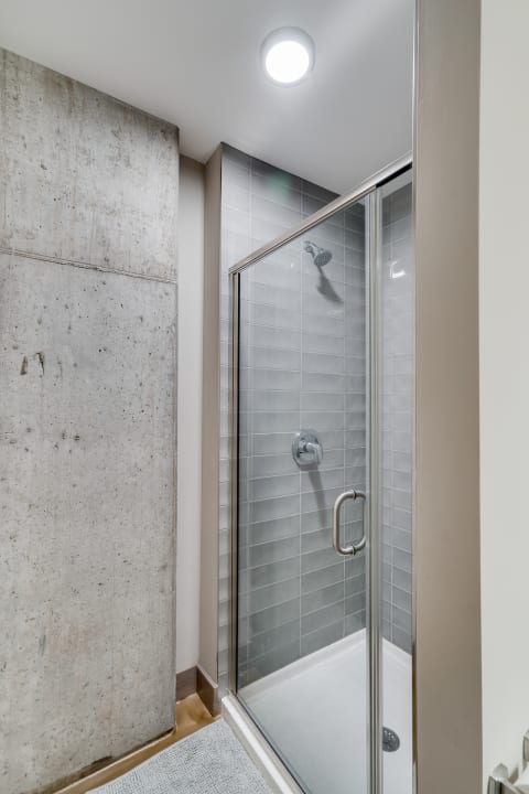 Modern shower stall with glass doors and gray tile walls.