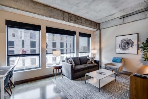 Modern living room featuring a gray couch, coffee table, and large windows with a construction view outside.