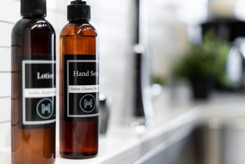 Two bottles of lotion and hand soap with stylish labels on a countertop.