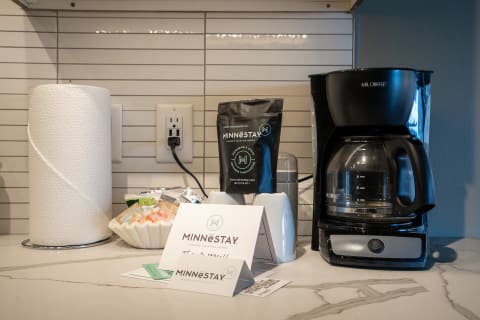A countertop with a coffee maker, coffee bag, and various amenities for guests.