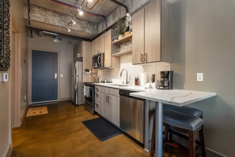 A stylish kitchen featuring modern appliances, light wood cabinets, and a marble countertop in an urban apartment setting.