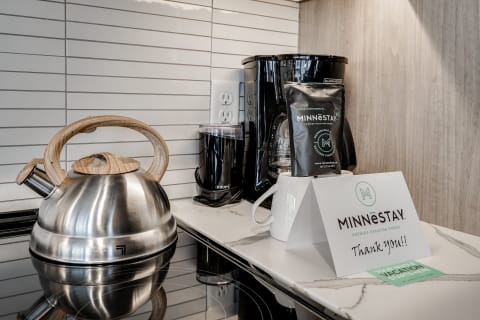 A kitchen counter with a kettle, coffee maker, and a thank-you card from Minnestay.