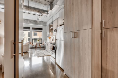 Interior view of a modern kitchen and dining space with light wood cabinetry and stainless steel appliances.