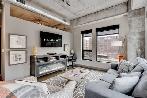 Contemporary living room with gray sofa, media console, and large windows.