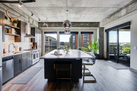 Modern kitchen with an island, dark cabinets, and large windows in an urban apartment.