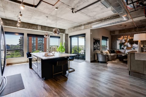 Interior of a modern apartment featuring a sleek kitchen island, large windows, and a cozy living area.