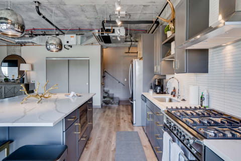 Modern kitchen featuring a central island, gray cabinetry, and industrial lighting.
