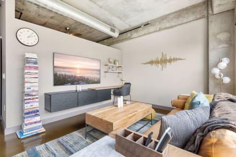 Modern living room featuring a flat-screen TV, decorative books, and a leather sofa with throw pillows.
