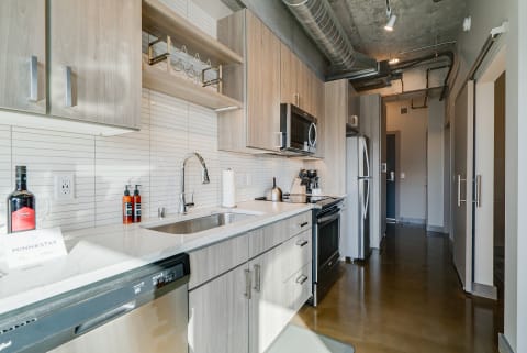 A contemporary kitchen featuring wooden cabinets, stainless steel appliances, and a polished countertop.