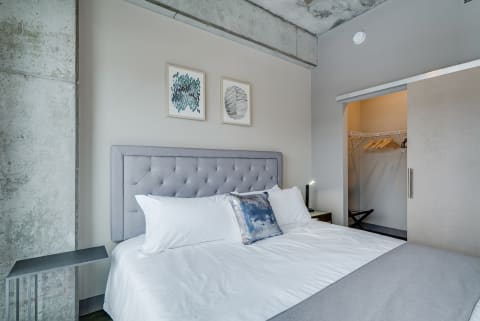 Contemporary bedroom with a grey tufted headboard, white linens, and modern decor.