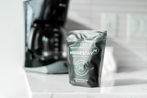 Gray coffee bag from MINNESTAY on a kitchen countertop next to a coffee maker.