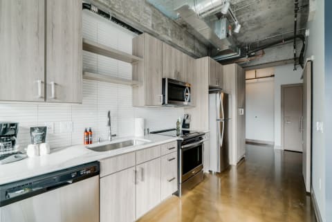 Modern kitchen with wooden cabinets, stainless steel appliances, and polished concrete floor.
