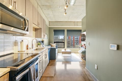 Interior of a modern apartment showing a kitchen and living area with urban views.