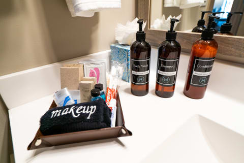 A neat bathroom counter displaying body wash, shampoo, conditioner, and various toiletries.