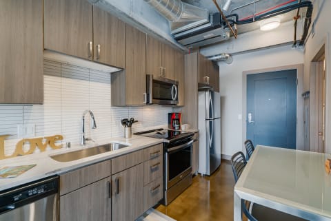Contemporary kitchen with wooden cabinets, stainless steel appliances, and a glass table.