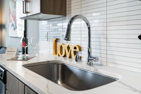 Modern kitchen countertop with a sink, chrome faucet, and decorative 'Love' sign.