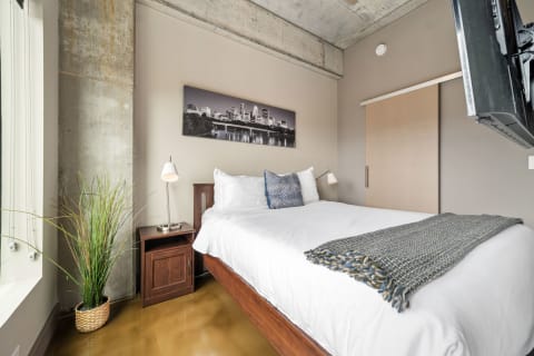 A stylish bedroom with a concrete wall, wooden furniture, and contemporary decor.