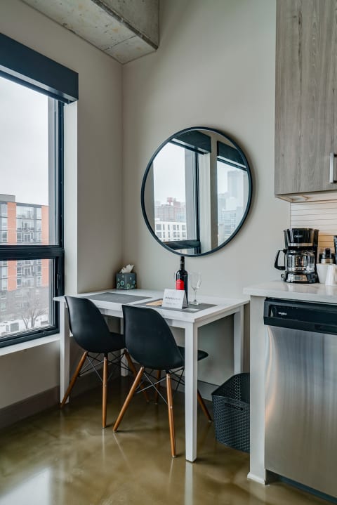 Cozy dining nook with a table, wine, and a city view through a large window.