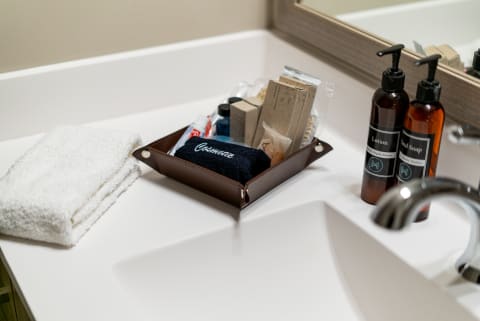 A bathroom countertop with towels and a tray of cosmetics and toiletries.