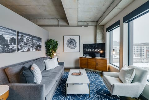 Modern living room with a gray sofa, wooden furniture, and snowy view outside.