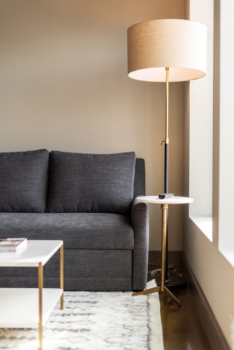 A gray sofa with cushions beside a floor lamp and small side table in a modern living room.