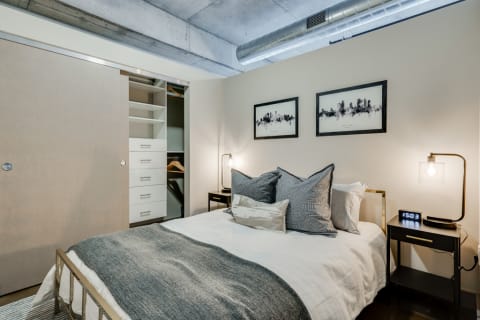 A modern bedroom with a cozy bed, textured pillows, and a built-in wardrobe.