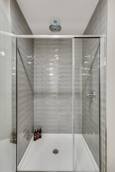 Interior of a modern shower stall with glass panels and gray tiles.